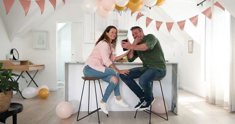 Happy Couple Celebrating at Home with Drinks and Decorations