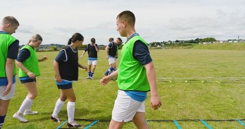 Soccer players running agility drills on field