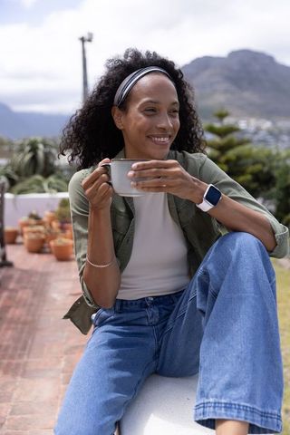 African american woman sipping coffee on rooftop garden with mountain view