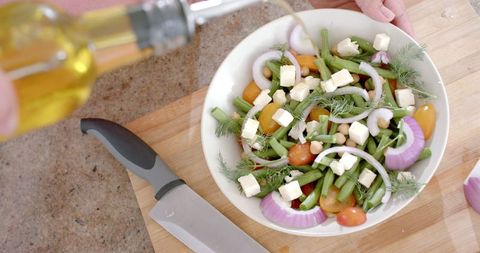 Healthy Vegetable Salad Being Prepared with Olive Oil in Modern Kitchen
