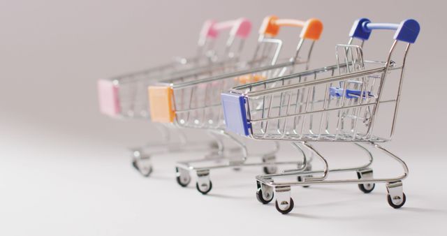Three Miniature Shopping Carts with Colorful Handles on Plain Background - Download Free Stock Photos Pikwizard.com