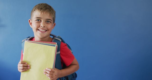 Happy Schoolboy with Backpack Holding Notebooks Against Blue Wall - Download Free Stock Images Pikwizard.com