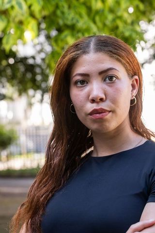 Standing african american woman wearing black top and hoop earrings in sunlit park