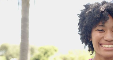 Cheerful Young Woman Smiling in Vibrant Outdoor Setting