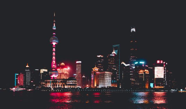 Stunning night view of Shanghai's skyline with brightly illuminated skyscrapers reflecting on the water. This cityscape captures the vibrance and energy of urban life, making it perfect for use in travel brochures, advertisements promoting business in Asia, or promotional materials emphasizing modern city living.