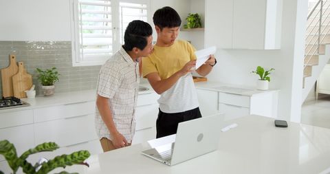 Father and Son Reviewing Documents in Modern Kitchen