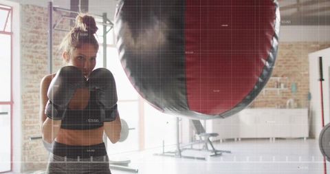Focused Woman in Gym Training with Punching Bag for Fitness