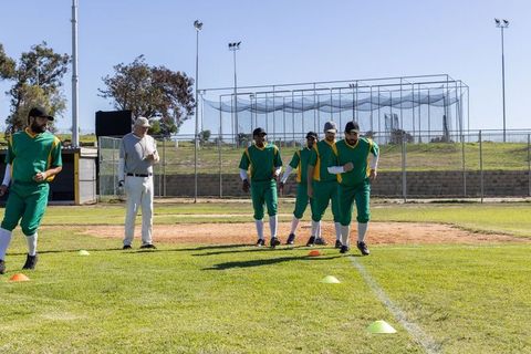 Amateur Baseball Team Practicing Agility Drills on Sunny Field with Coach Observing
