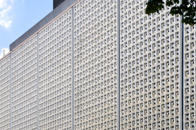 This stock photo highlights a modern architectural facade adorned with a repeating geometric pattern. Ideal for use in articles or presentations on contemporary architecture, urban design, or construction projects. Can be utilized in promotional materials for architectural firms or urban development projects.