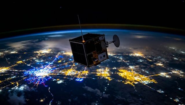 CubeSat orbiting above nightside Earth with city lights, airglow, antenna and solar panels