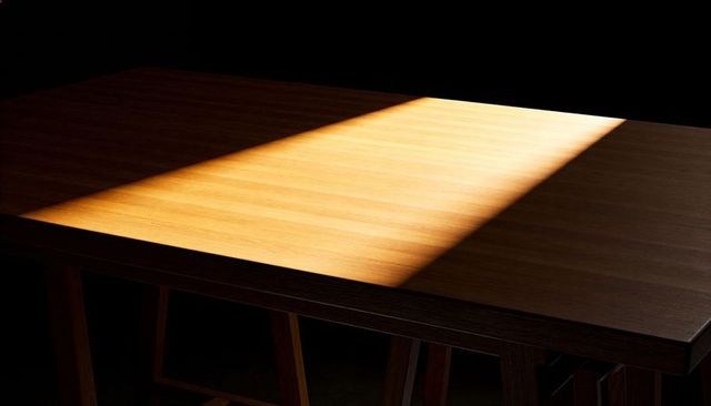 Sunbeam cutting across wooden table with warm grain and deep shadows