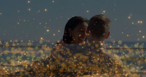 Couple embracing on waterfront with dreamy golden lights