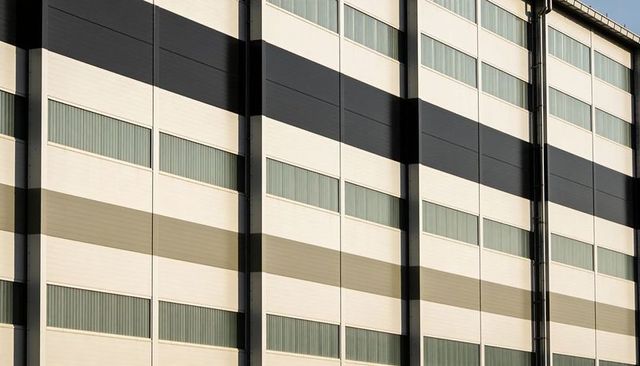 Modern industrial warehouse facade with bold horizontal stripes and vertical columns