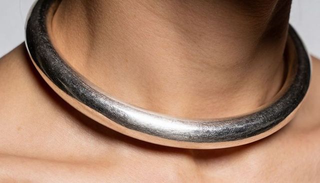 Bold silver choker closeup showing hammered metal texture and collarbone elegance