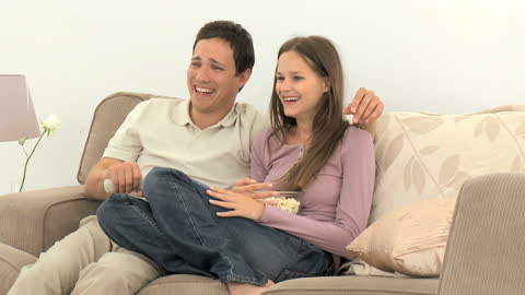 Happy Couple Enjoying Movie Night on Sofa at Home