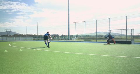Teen field hockey player driving toward goal on turf field