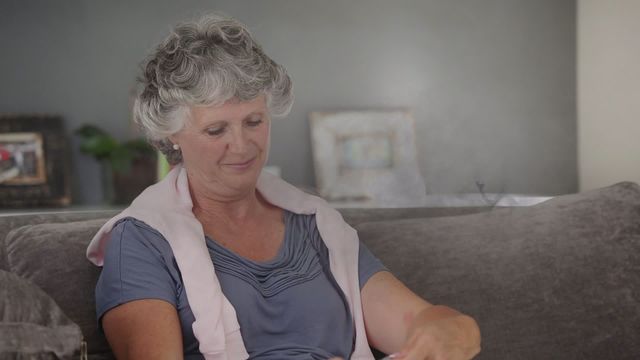 Grey smoke adds a peaceful effect as a senior woman knits at home. Perfect for topics on relaxation, hobbies for the elderly, or creative uses of light and video effects.