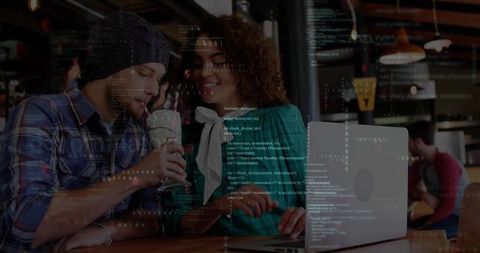 Young developers collaborating on laptop in urban cafe coding together over coffee