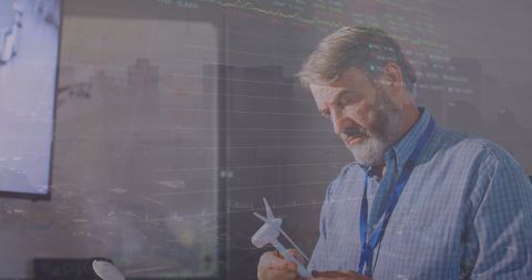 Engineer Designing Wind Turbine Against Financial Data Overlay