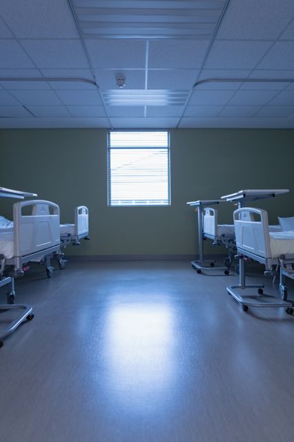 Modern hospital ward featuring empty beds and natural light coming through a window. Ideal for use in healthcare, medical, and hospital-related content, showcasing clean and sterile environments, patient care facilities, and modern medical equipment.