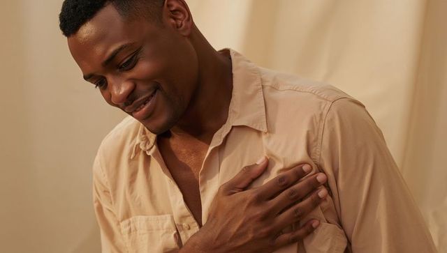 African american man placing hand on chest, warm smile, intimate beige studio portrait