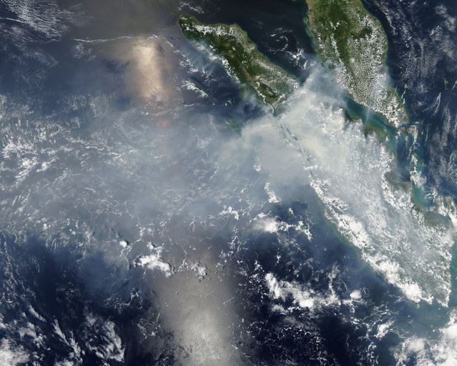 Heavy smoke and haze cover Sumatra, Indonesia, due to widespread fires designed for land clearing. Captured by NASA’s Aqua satellite on March 12, 2014, this true-color image highlights the severe environmental impact and visibly demonstrates poor air quality over the region. Thick bands obscure much of Riau region compelling school and flight cancelations and leading to hazardous living conditions. Useful for understanding pollution, environmental emergencies, land management, and the effects of illegal farming practices.