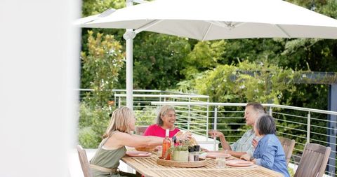 Senior Friends Enjoying Meal Outdoors Under Patio Umbrella - Download Free Stock Images Pikwizard.com