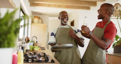 Father son kitchen bonding with aprons and drinks