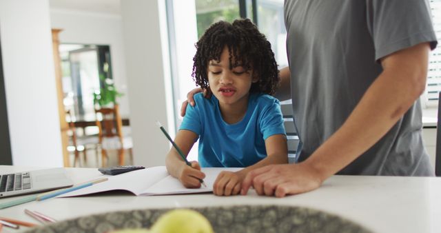 Child writing homework at table with parent offering assistance and support in comfortable home environment. Useful for educational content, parenting articles, home learning tips, and family bonding themes.