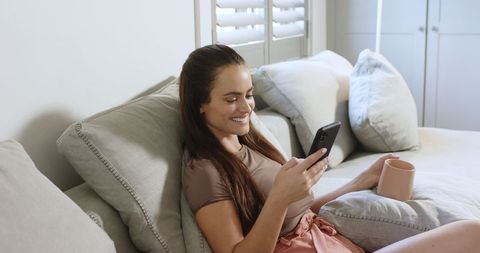 Woman Enjoying Leisure Time with Smartphone and Coffee at Home