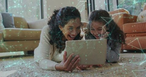 Smiling mother and daughter sharing tablet on living room rug with global network overlay