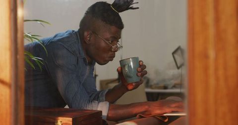 Thoughtful craftsman drinking coffee in leather workshop