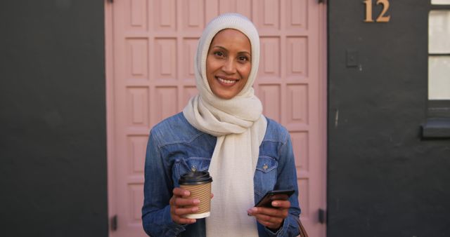 Smiling Woman in Hijab Holding Coffee and Smartphone - Download Free Stock Images Pikwizard.com