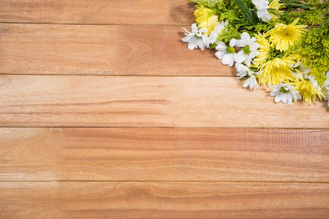 Fresh flowers, including white daisies and yellow blooms, arranged on a wooden board. Ideal for use in spring or summer-themed designs, nature-related projects, floral decorations, or as a rustic background for invitations, greeting cards, or social media posts.