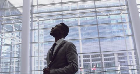 Ambitious businessman looking upward with optimism in modern office