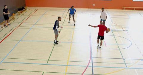 Male team captain calling play on indoor basketball court holding ball during pickup game