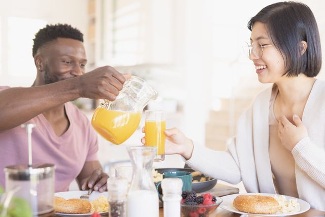 Happy diverse couple eating breakfast together in kitchen. Spending quality time at home, domestic life and lifestyle concept.