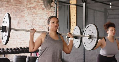 Women lifting barbells in industrial gym building strength and confidence during training