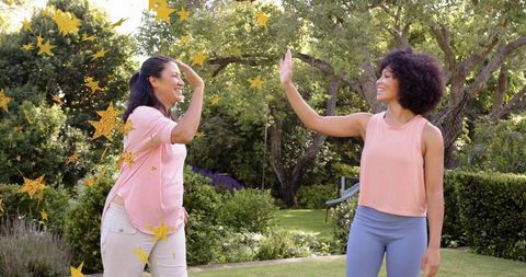 High-fiving friends in garden celebrating workout success with gold star confetti