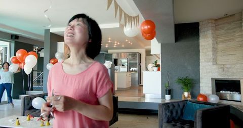 Joyful seniors preparing birthday celebration decorations indoors