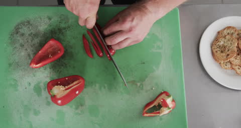 Chef Cutting Red Bell Peppers on Green Chopping Board