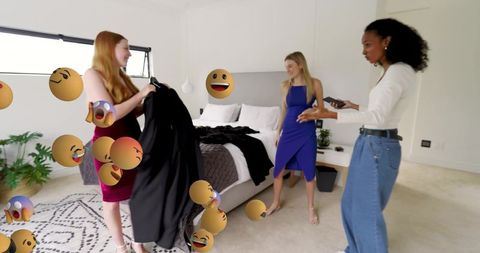 Women styling dresses in modern bedroom with floating emoji reactions and smartphone