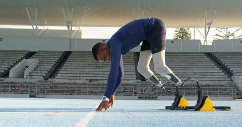 Disabled athlete with prosthetic legs prepares for race on track