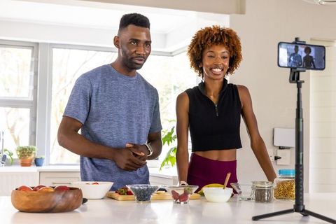 African american couple filming healthy breakfast bowls in bright modern kitchen