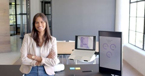 Confident Businesswoman Standing at Modern Office Desk with Charts
