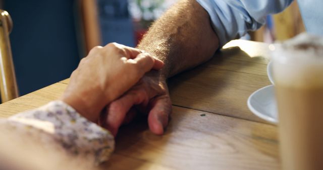 Senior Caucasian couple holding hands at home, with copy space. Their gesture conveys a lifetime of companionship and mutual support.