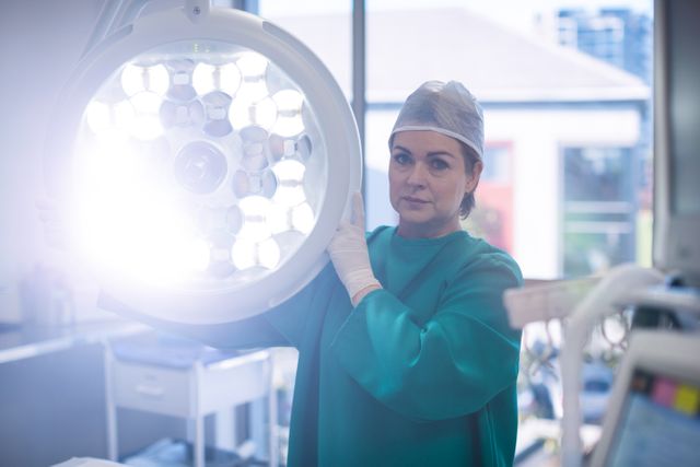 Portrait of surgeon adjusting surgical light in operation room at hospital