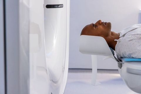African american man undergoing mri scan lying on table with head coil in radiology suite