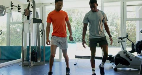 Trainer Guiding Client in Fitness Routine at Gym