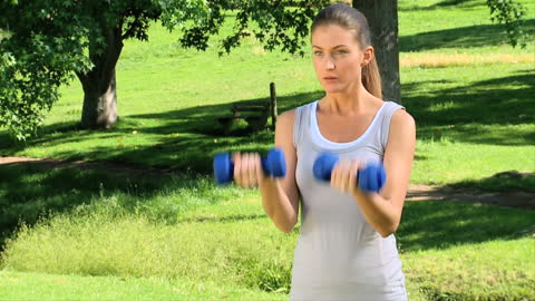 Woman Exercising with Dumbbells in Sunny Park